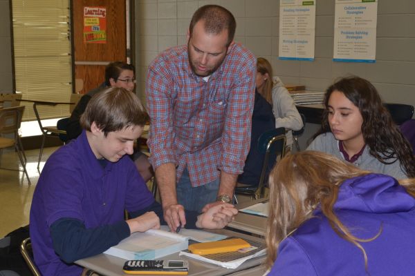 MR. JEFFERY MULLINS HELPS STUDENTS UNDERSTAND THEIR ALGEBRA I ASSIGNMENT-- One of Centrals Algebra I teachers, Mr. Mullins, helps students with their work after teaching a lesson.