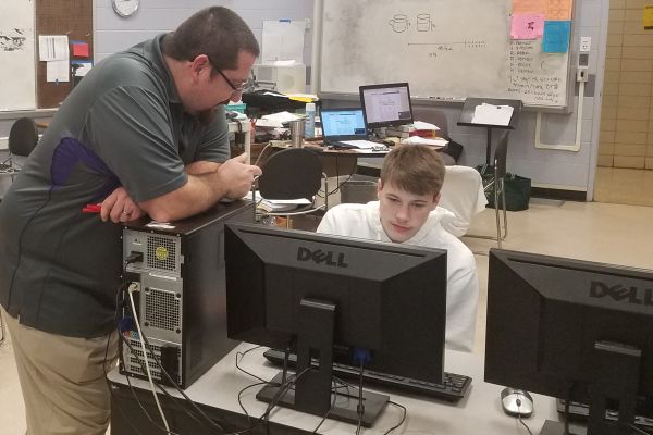 TEACHER SPOTLIGHT: MR. POTTER, MASTER OF DAD JOKES AND ADVANCED MATH -- Mr. Potter helps student, Brett Abshire, with a math problem in the computer lab.