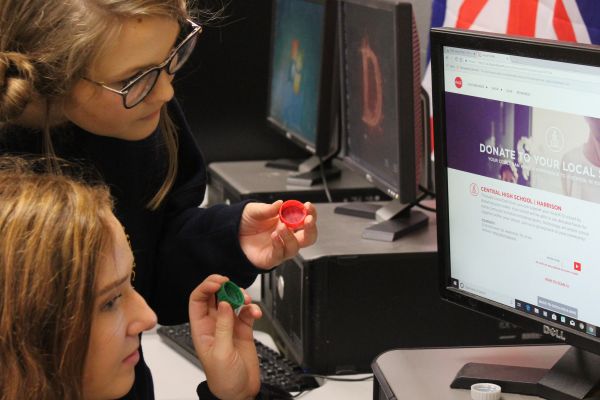 DONATE YOUR COKE CAPS TO THE CENTRAL DIGEST -- Staff members Laurelie Holmberg and Amber King are depicted entering codes from Coke tops into the computer.