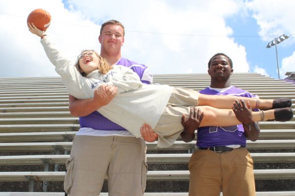 STUDENT SECTION OR SENIOR SECTION? -- Senior football players Wyatt Garret (left) and Michael Mcghee (right) hold Columnist Laurelie Holmberg up to catch a ball.