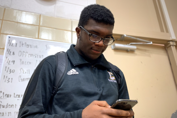 THE PROS AND CONS TO SOCIAL MEDIA -- Junior, Jailon Jackson has his eyes locked on his phone as he stands in the gym. 