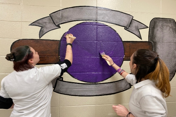 ART STUDENTS PAINT BASKETBALL MURAL IN BOYS LOCKER ROOM -- Juniors Vivian Lakey and Sophomore Zaida Aucoin are hard at work on the new basketball mural.