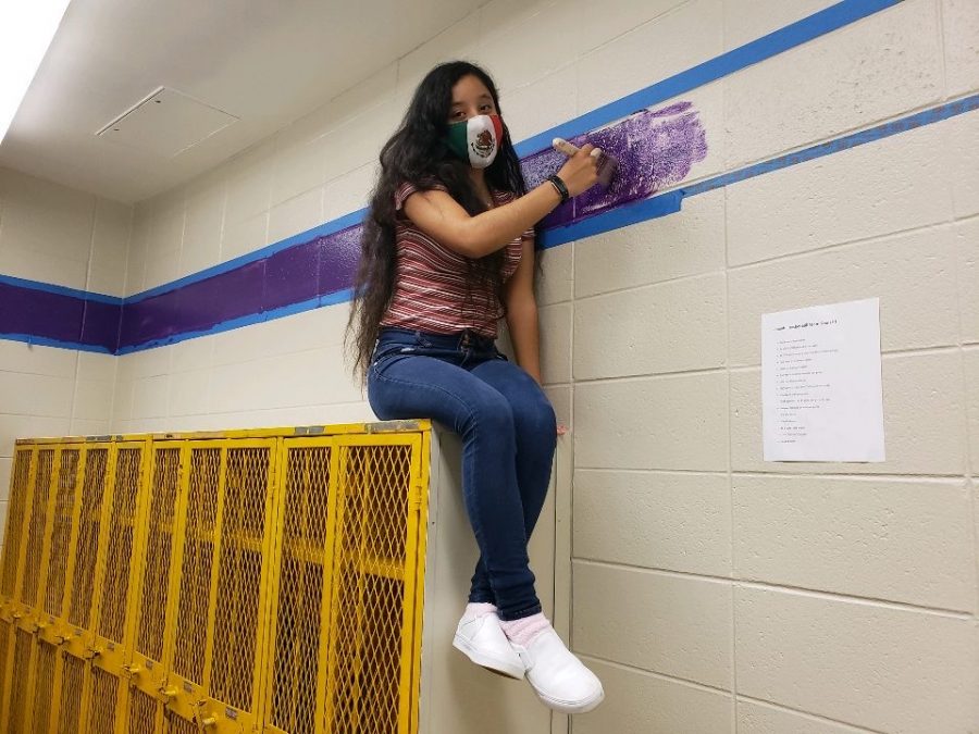 2020 LEADERSHIP CLASS TOUCHES UP THE WALLS OF CENTRAL-- Senior Dallana Nolazco sits on a locker while touching up the walls of the basketball locker rooms. 
