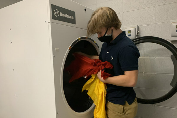 THE SPORTS DEPARTMENTS NEW DRYER -- Senior Roby Thomas puts practice gear in the dryer to dry. 