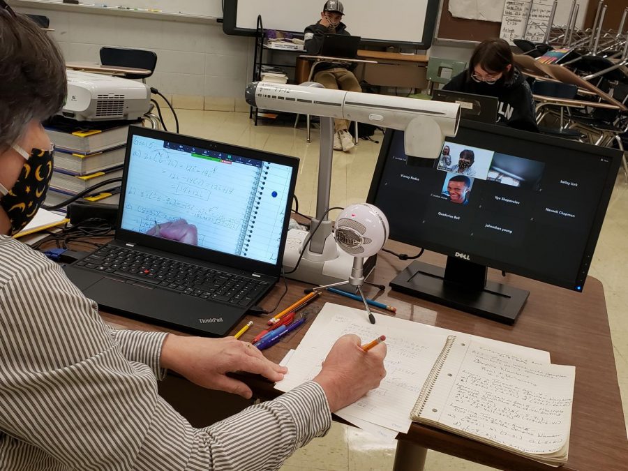 COVID-19 PANDEMIC CAUSES A DROP IN MATH COMPREHENSION -- Peggy Moyer is teaching her students on campus and through Zoom. She uses her Elmo to project what she writes to both groups of students.