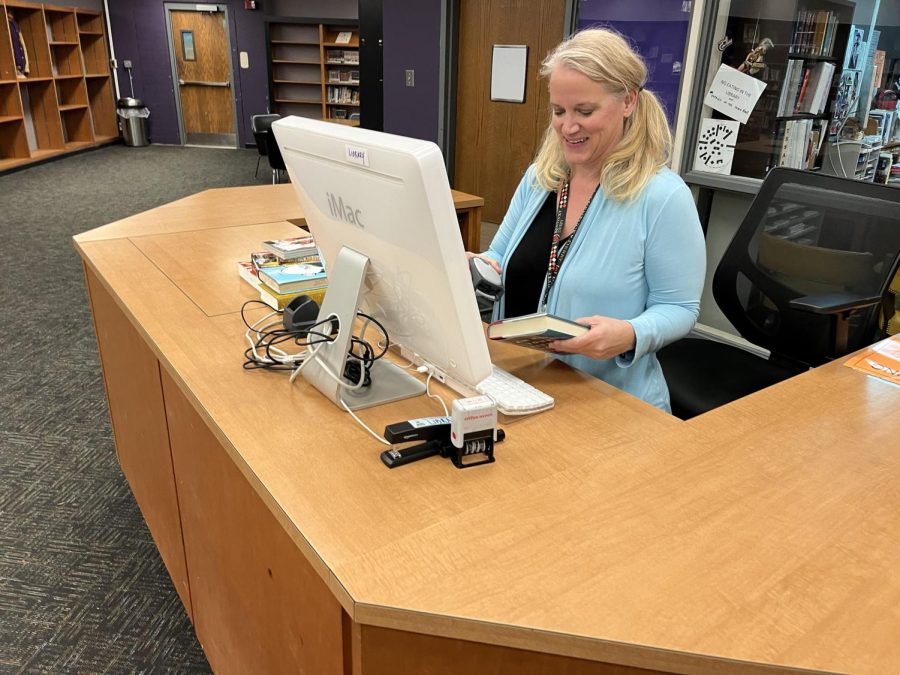 Mrs. MARTIN HANDLING A BOOK IN CENTRAL HIGH SCHOOL's LIBRARY